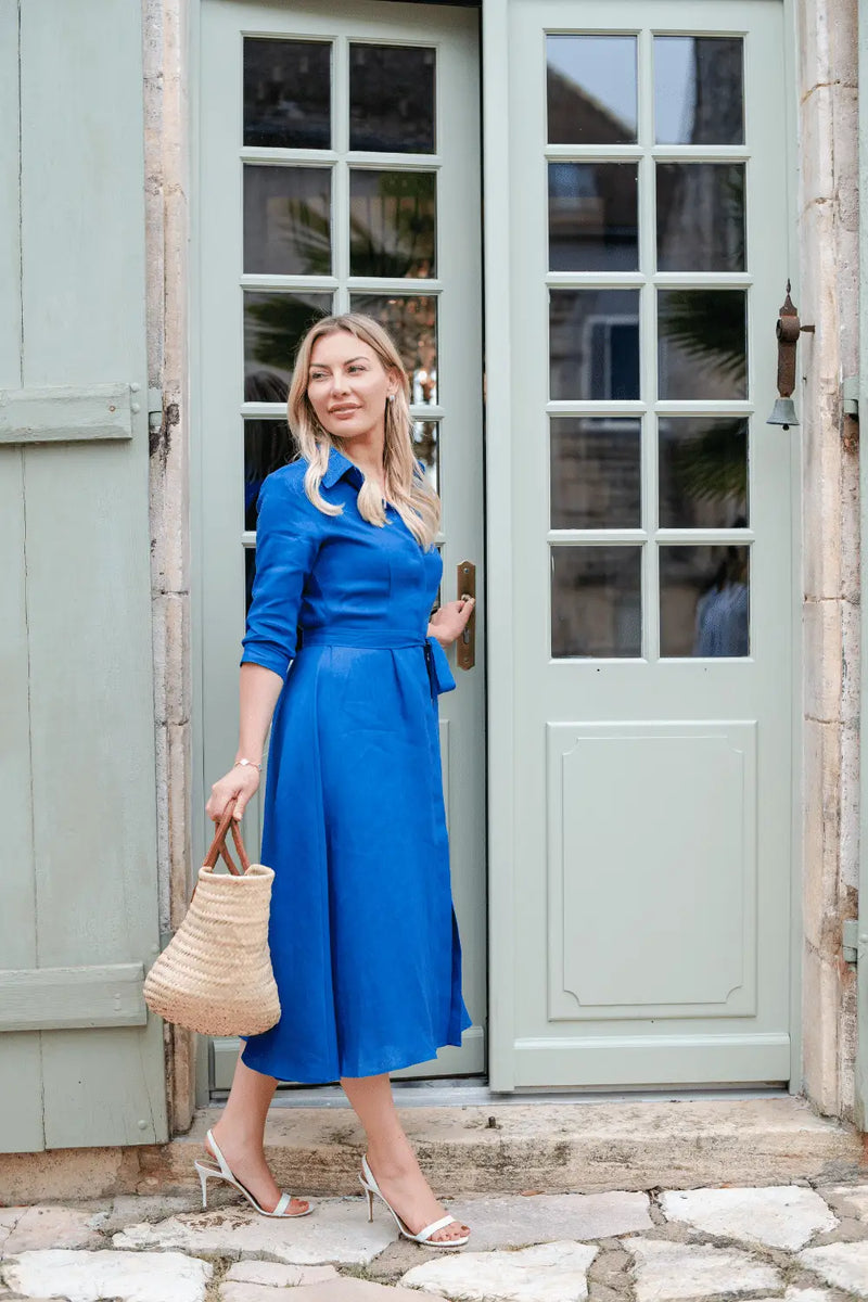 Anna Bey opens the door in her signature blue linen shirt dress