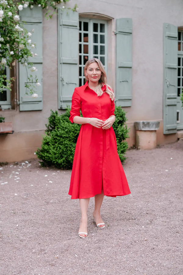 Anna Bey standing in a garden in her signature linen dress in red