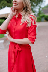  Close-up of Anna Bey in a red linen dress standing in a garden